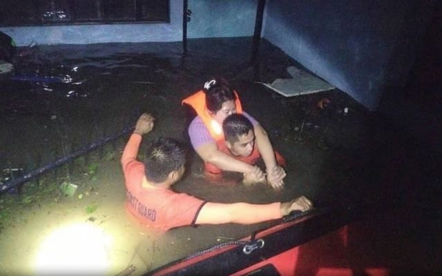 Rescuers carry a resident to safer grounds in Guinobatan, Albay province