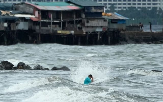 A resident swims in strong waves caused by Trami in Manila