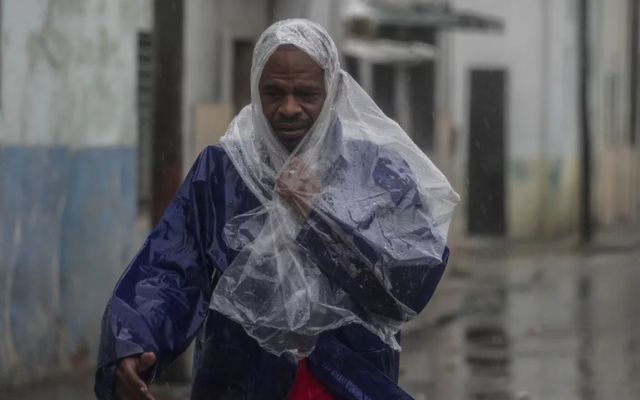 A man walks through the wind and rain brought by Hurricane Rafael